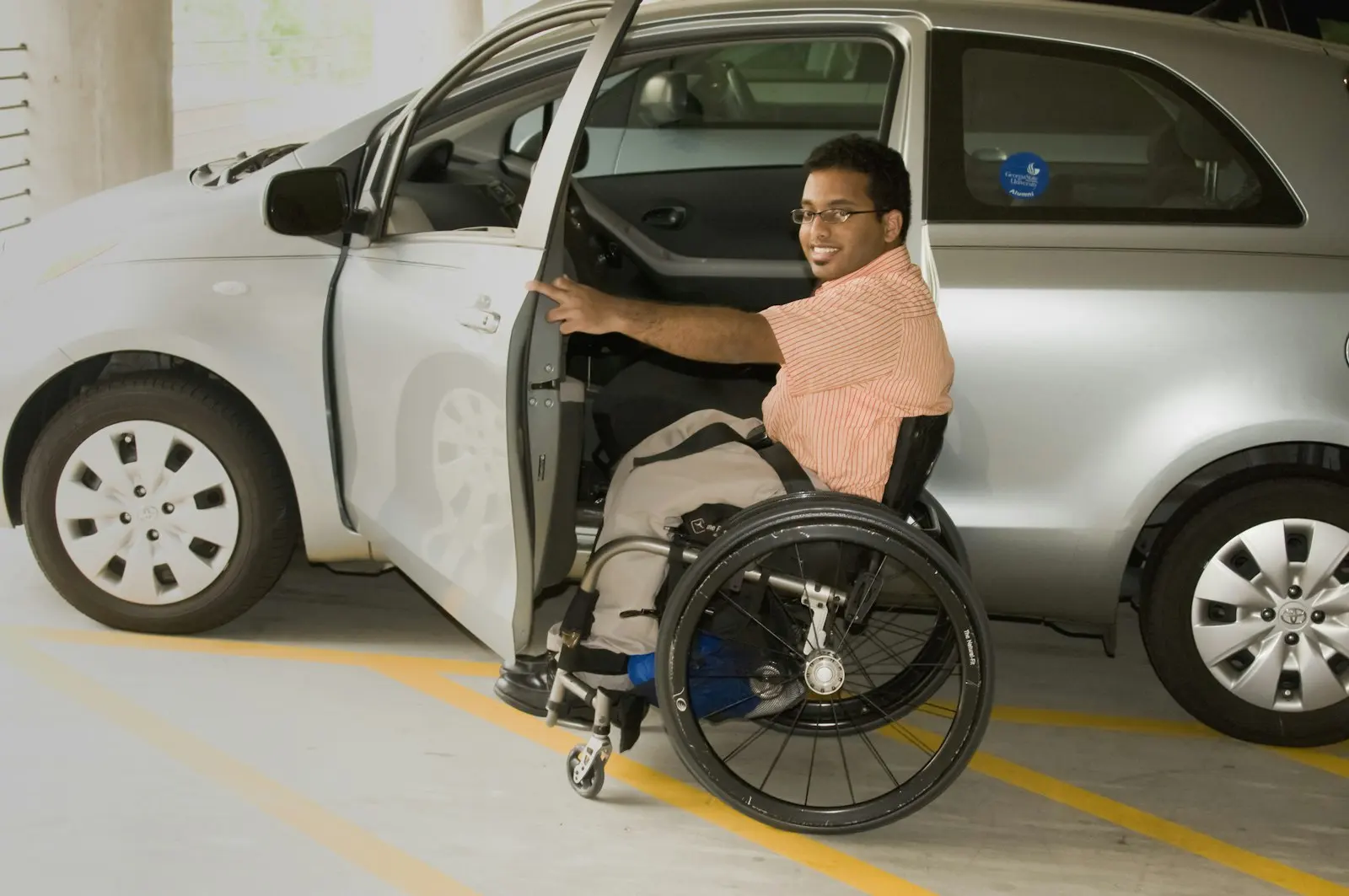 A rider moving from his wheelchair into a car with the door held open